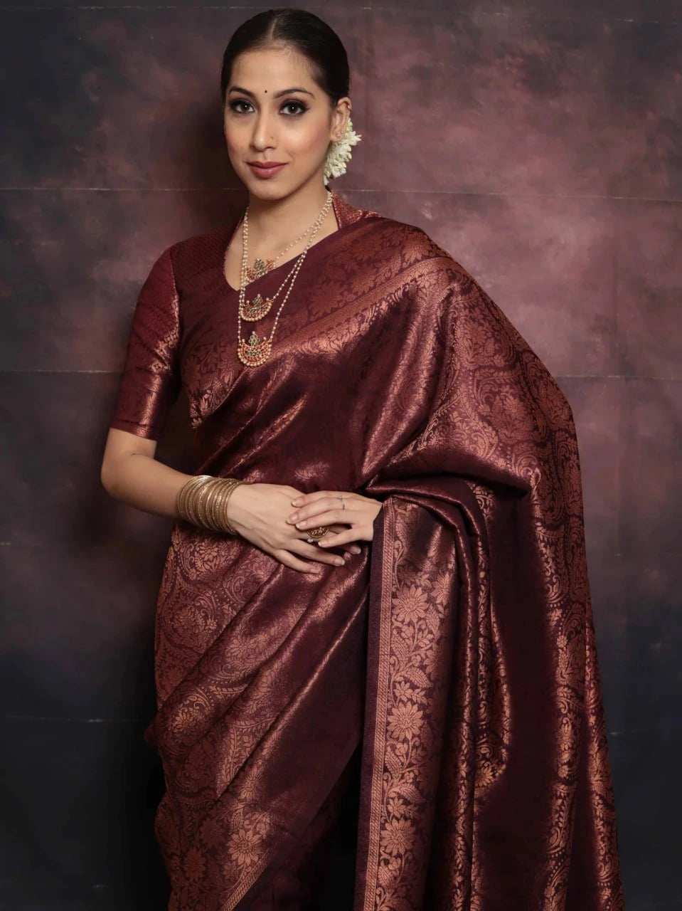 Woman wearing a maroon saree with a dark background